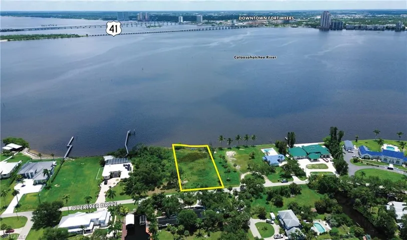 Aerial perspective of suburban area featuring a large body of water and property boundaries highlighted