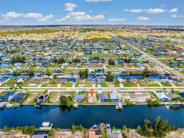 Aerial view of property and surrounding area featuring nearby suburban area and a nearby body of water