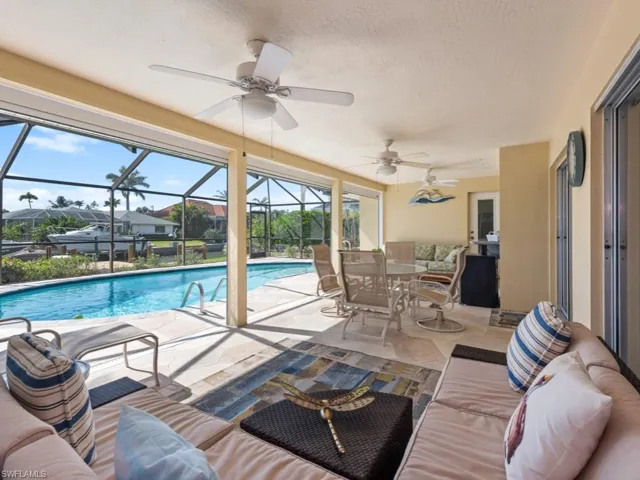 Pool with an outdoor living space, glass enclosure, a patio, and a ceiling fan
