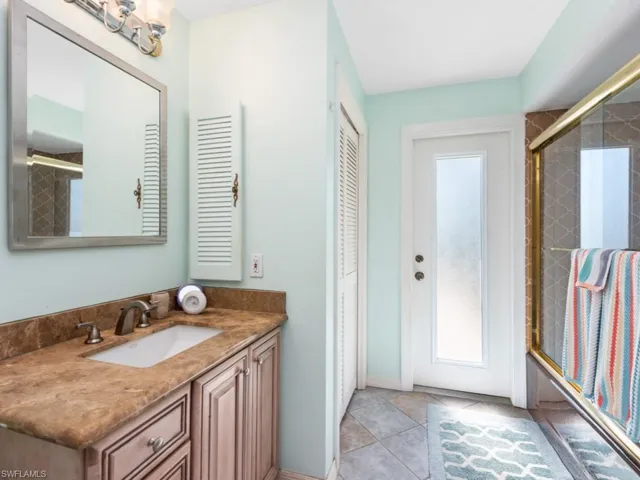 Full bath with combined bath / shower with glass door, tile patterned floors, and vanity