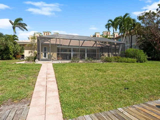 Rear view of house with glass enclosure, a lawn, and stucco siding