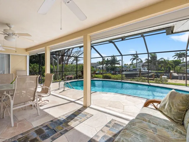Pool featuring a patio area, ceiling fan, and glass enclosure