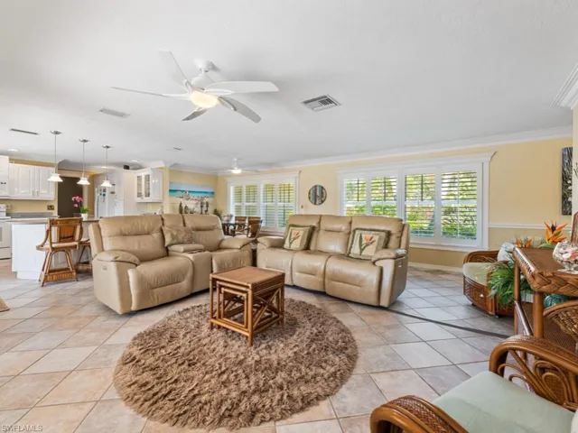 Living area featuring crown molding, light tile patterned floors, a ceiling fan, and visible vents