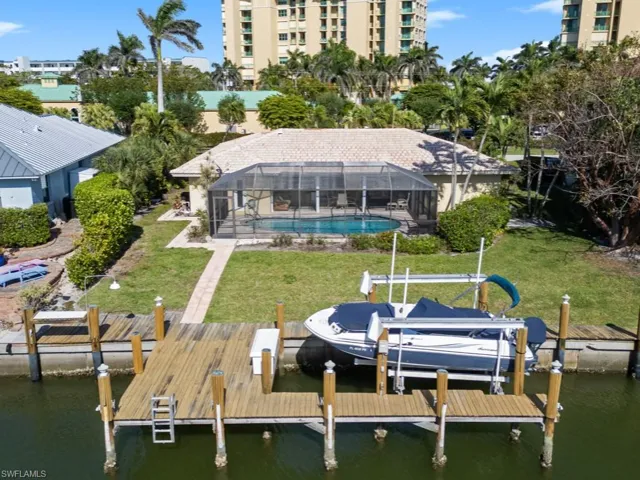 Dock area with an outdoor pool, boat lift, a yard, and a water view