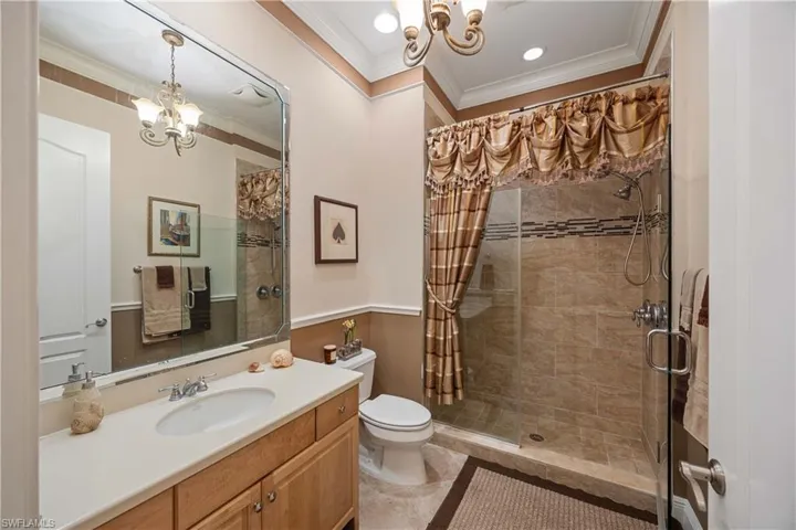 Full bath with a chandelier, vanity, a shower stall, crown molding, and light tile patterned flooring