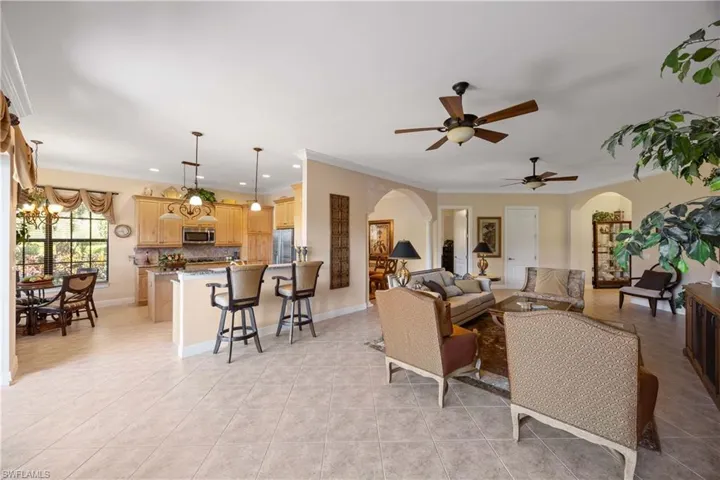 Living area featuring arched walkways, crown molding, light tile patterned floors, a chandelier, and recessed lighting