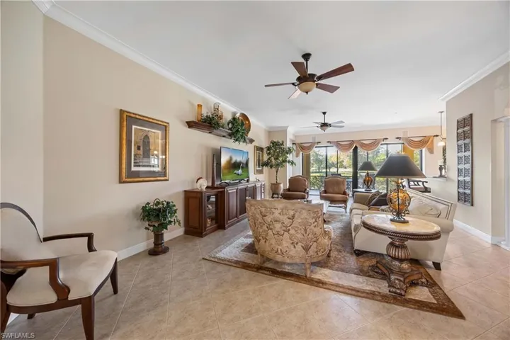 Living room with light tile patterned floors, crown molding, and ceiling fan