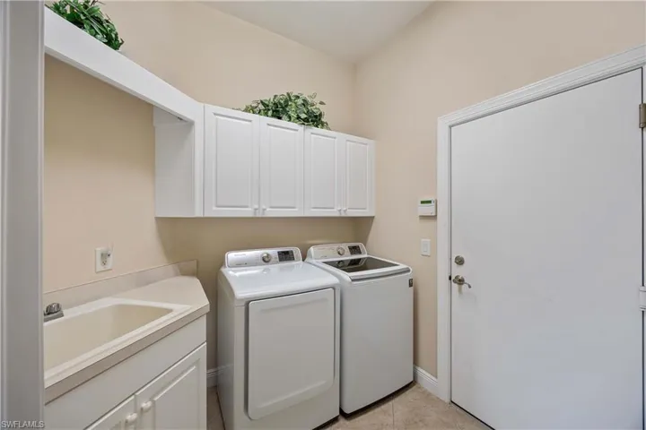 Laundry room featuring cabinet space, independent washer and dryer, and light tile patterned flooring