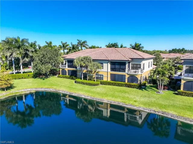 Rear view of property with a yard, a balcony, stucco siding, and a water view