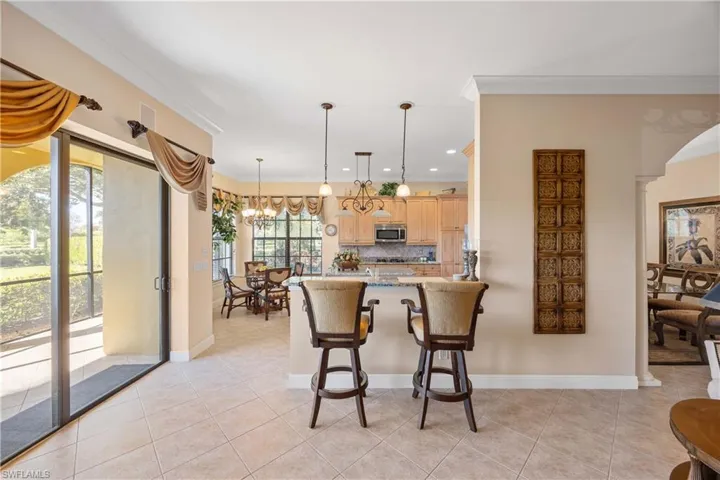 Kitchen with a breakfast bar, pendant lighting, dark stone counters, backsplash, and light tile patterned floors