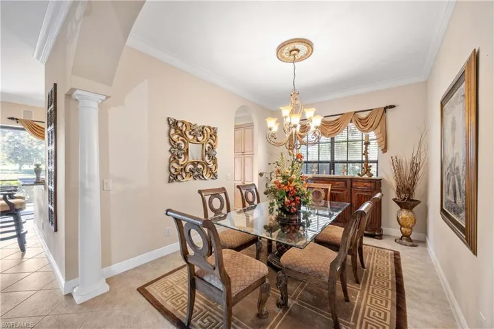 Dining space with decorative columns, crown molding, arched walkways, a chandelier, and plenty of natural light