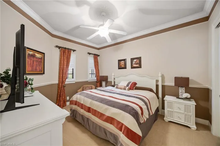 Bedroom with a ceiling fan, crown molding, and light colored carpet