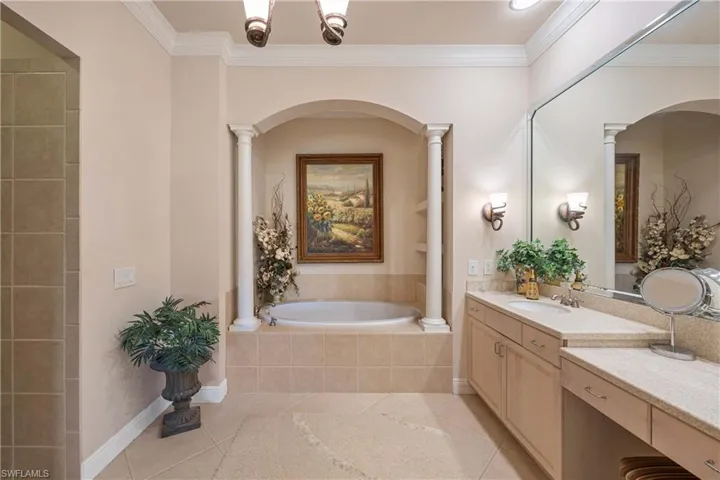 Bathroom with vanity, a bath, light tile patterned floors, crown molding, and decorative columns