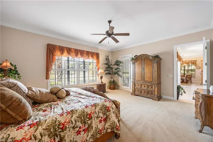 Carpeted bedroom featuring multiple windows, ceiling fan, and crown molding