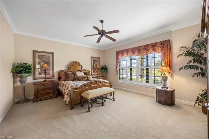 Carpeted bedroom featuring ornamental molding and a ceiling fan