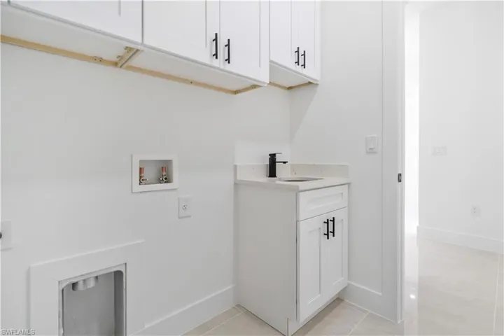 Laundry space featuring white shaker cabinetry with matte black hardware, a light-colored countertop, and a built-in sink with a matte black faucet