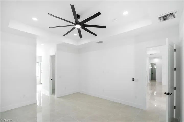 Spacious room with a tray ceiling, recessed lighting, and a modern black ceiling fan