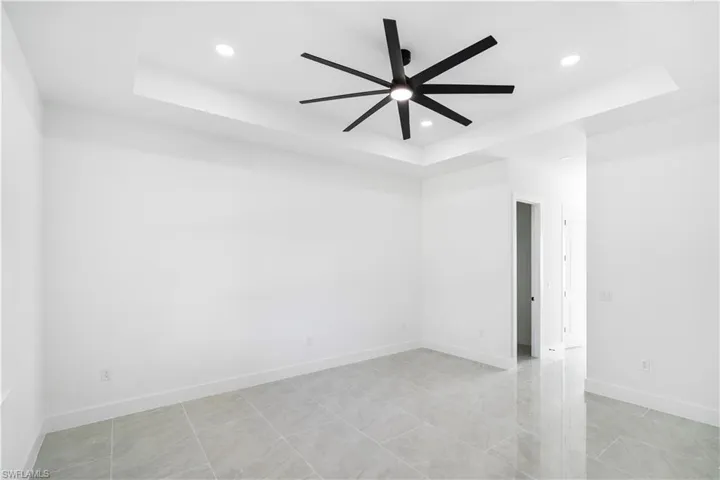 Spacious room featuring a tray ceiling with recessed lighting and a contemporary ceiling fan