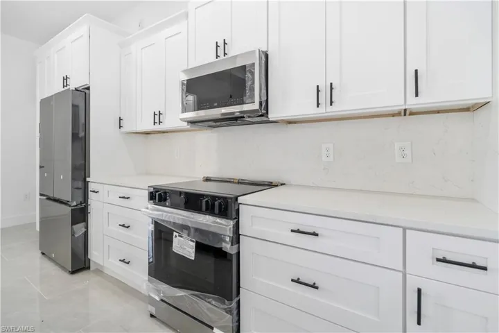 Modern kitchen featuring white shaker cabinetry with matte black hardware