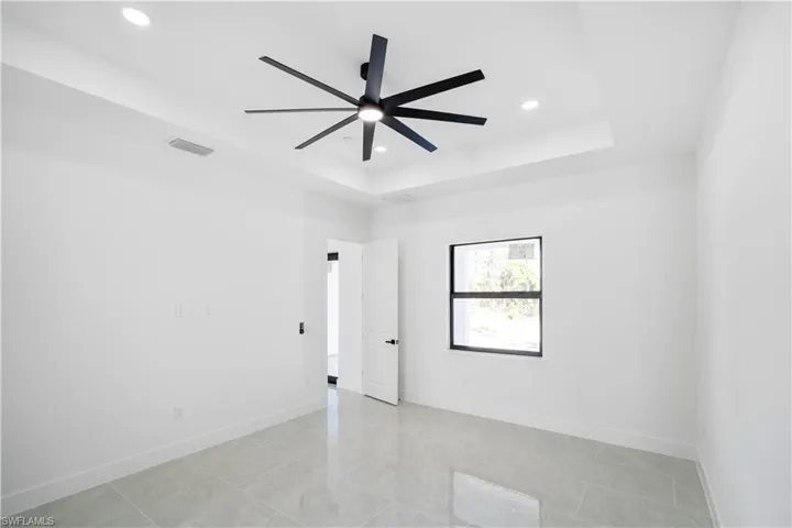 Spacious room with tray ceiling, recessed lighting, and a modern ceiling fan