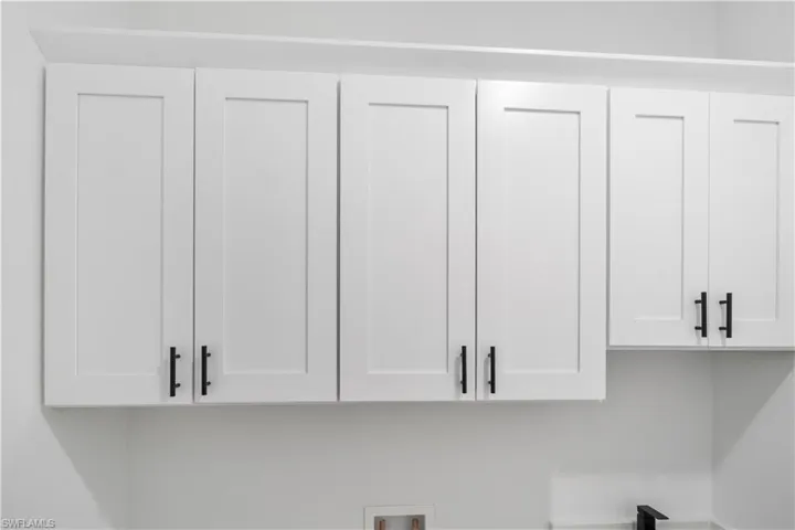 White shaker-style cabinetry with matte black hardware, featuring a crown molding detail and ample overhead storage