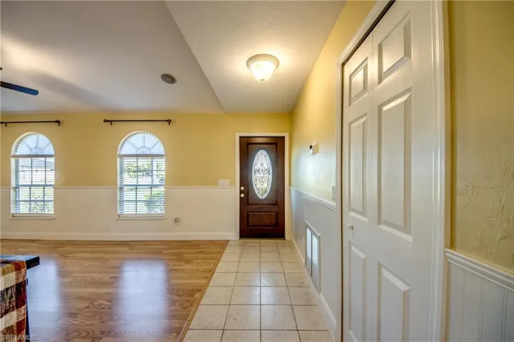 Tiled foyer entrance featuring a dark cherry impact-rated front door with decorative glass inlay.