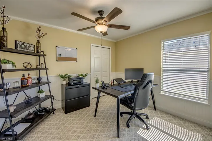 Guest bedroom with light colored farmhouse-style carpeting, plenty of natural light, crown molding, and smart home capable ceiling fan. Perfect to use as an in-home office.