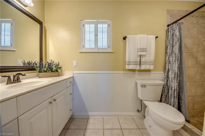 Master bathroom with beautiful crown molding, light colored tile, picture frame-style mirror, and vanity with extensive cabinet and countertop space.