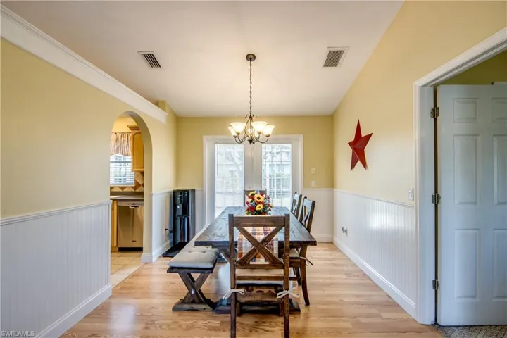 Formal dining area featuring light wood-type floors as well as an inviting chandelier and a set of beautiful white French doors that access oversized patio.