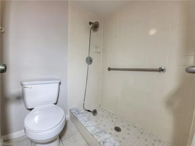 Bathroom featuring tile patterned flooring, toilet, and tiled shower