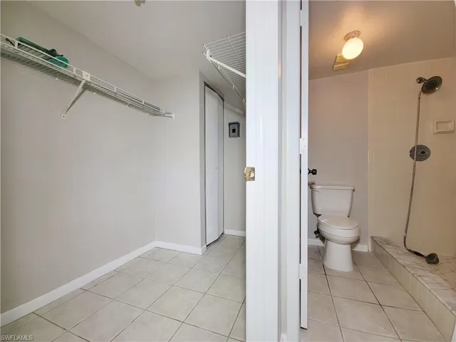 Bathroom with tile patterned flooring, a tile shower, and toilet