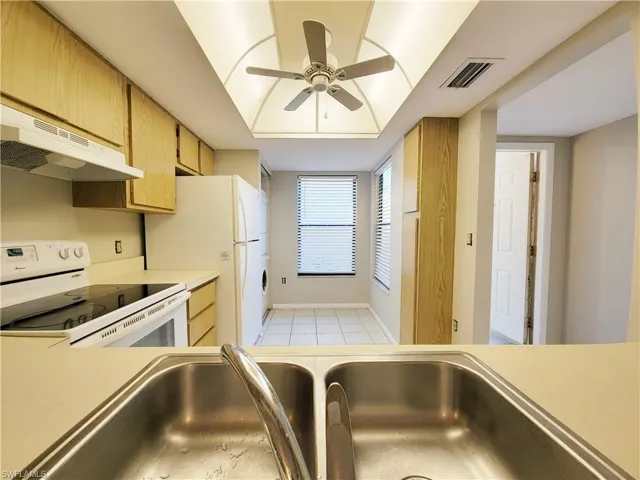 Kitchen with ceiling fan, sink, light tile patterned floors, and white appliances