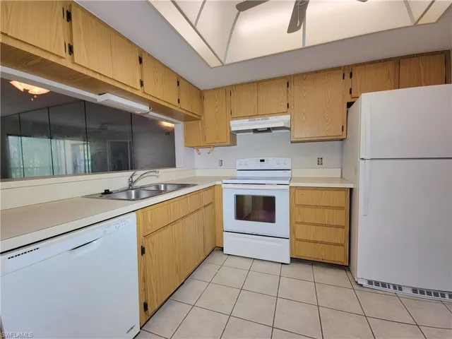 Kitchen with ceiling fan, sink, light tile patterned floors, and white appliances