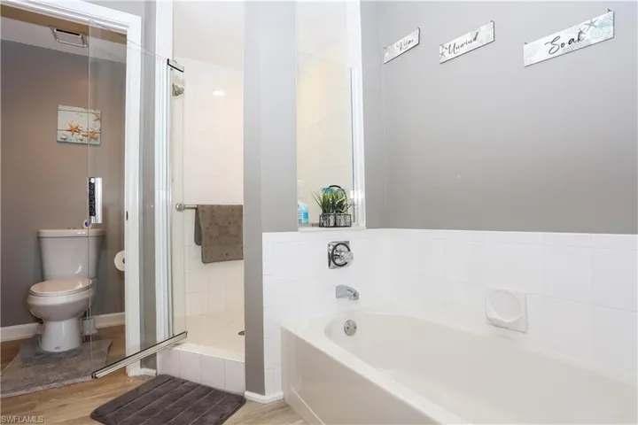 Full bath featuring a shower stall, a garden tub, and light wood finished floors