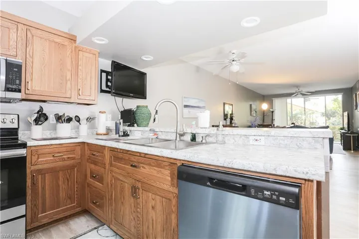 Kitchen with stainless steel appliances, light countertops, a peninsula, open floor plan, and a ceiling fan