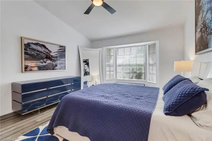 Bedroom with hardwood / wood-style floors, ceiling fan, and vaulted ceiling