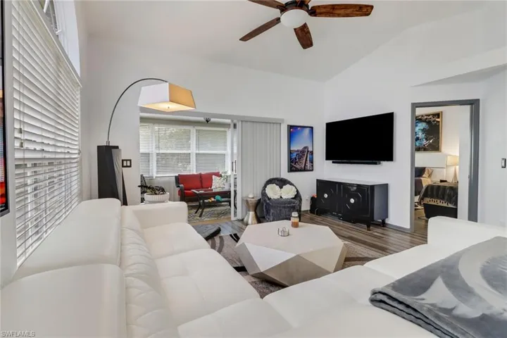 Living room featuring wood-type flooring, ceiling fan, and vaulted ceiling