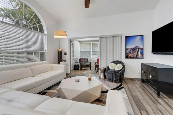 Living room featuring light hardwood / wood-style floors, a healthy amount of sunlight, ceiling fan, and vaulted ceiling