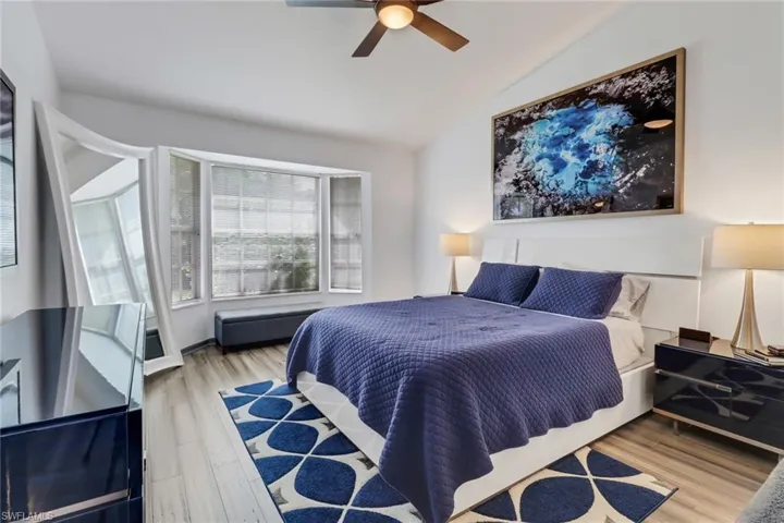 Bedroom with ceiling fan, light hardwood / wood-style flooring, and vaulted ceiling