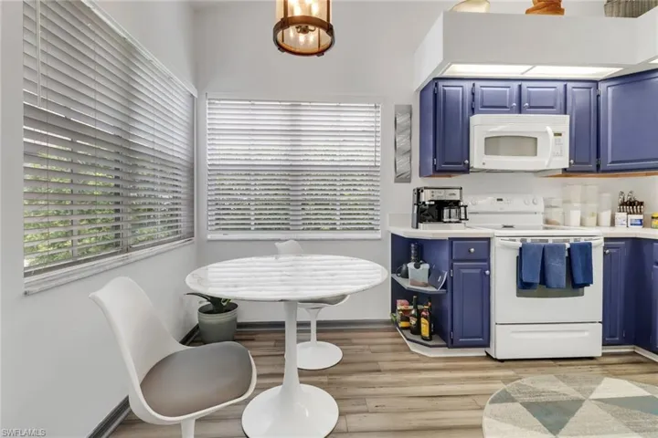 Kitchen featuring an inviting chandelier, light hardwood / wood-style flooring, white appliances, and blue cabinetry