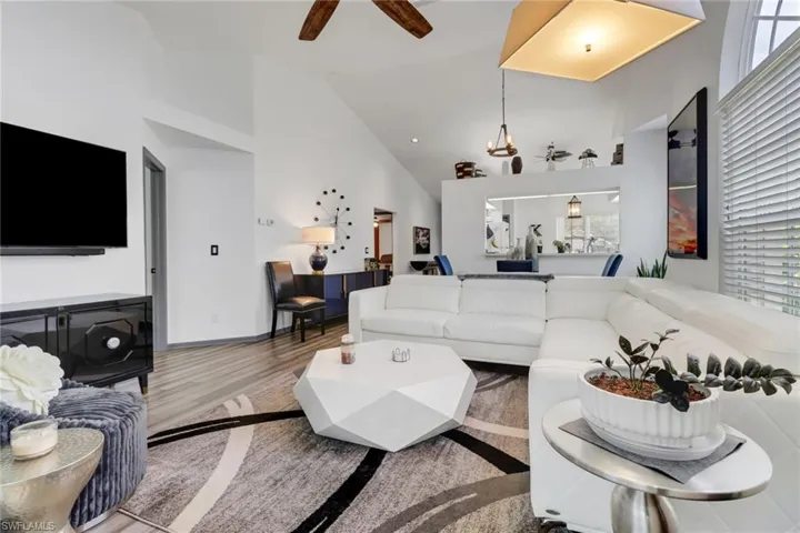 Living room with light hardwood / wood-style flooring, high vaulted ceiling, and ceiling fan