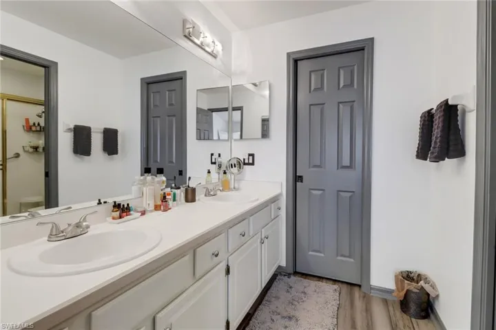 Bathroom with dual vanity, hardwood / wood-style flooring, and toilet
