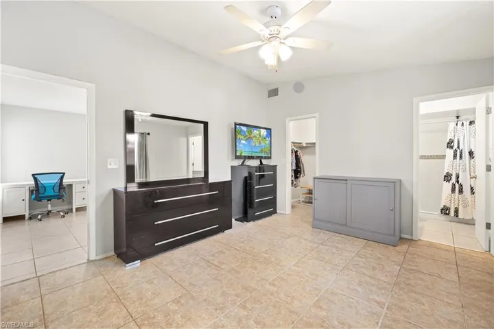 Bedroom featuring visible vents, a walk in closet, connected bathroom, a ceiling fan, and light tile patterned floors