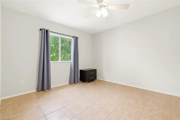 Unfurnished room featuring baseboards, ceiling fan, and light tile patterned floors