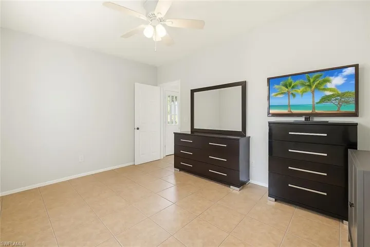 Unfurnished bedroom featuring a ceiling fan, baseboards, and light tile patterned floors