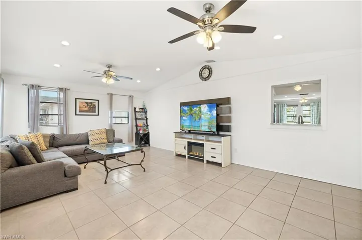 Living area with recessed lighting, ceiling fan, light tile patterned floors, and lofted ceiling