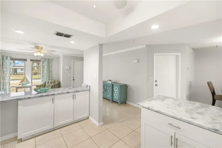 Kitchen featuring a ceiling fan, visible vents, light tile patterned floors, baseboards, and white cabinets