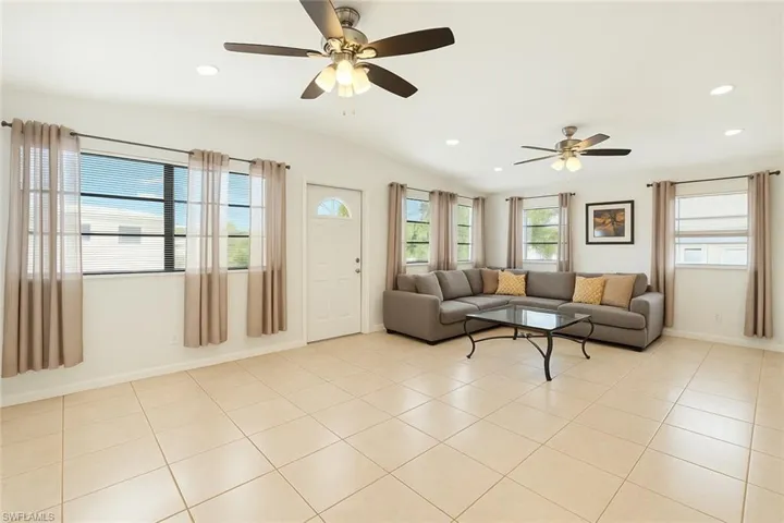 Living area with ceiling fan, recessed lighting, baseboards, light tile patterned floors, and vaulted ceiling