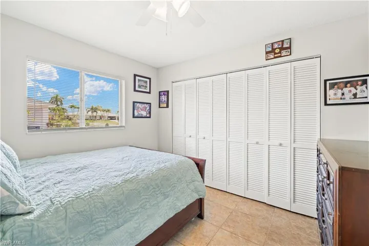 Bedroom with ceiling fan, light tile patterned floors, and a closet
