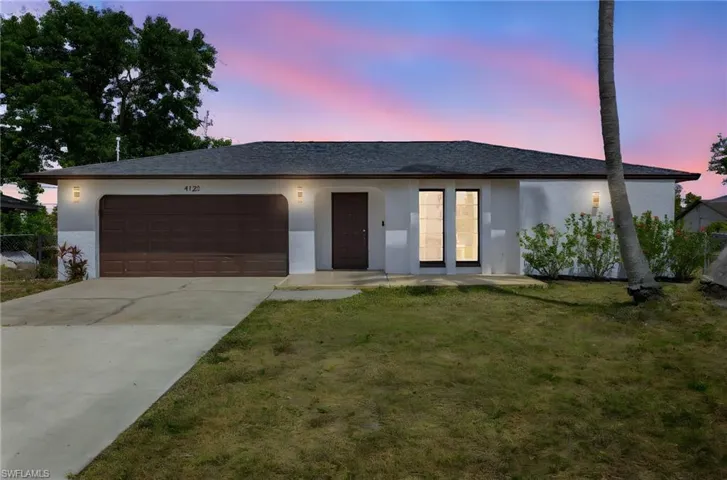 Ranch-style house with concrete driveway, a lawn, stucco siding, and an attached garage